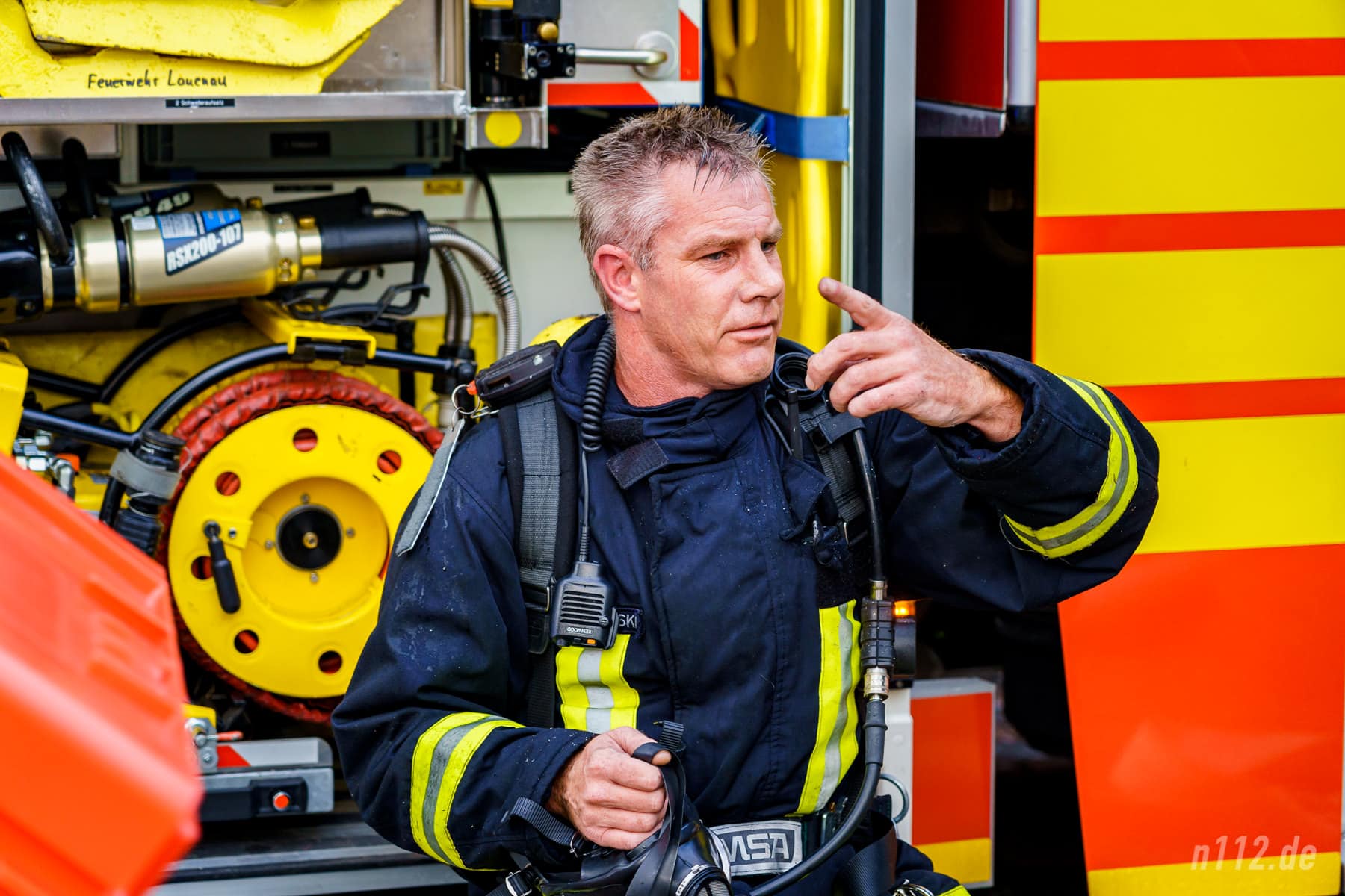 Ordentlich verschwitzt und mit verrauchter Einsatzkleidung sitzt dieser Feuerwehrmann nach seinem Einsatz unter Atemschutz an einem Löschfahrzeug (Foto: n112.de/Stefan Hillen)
